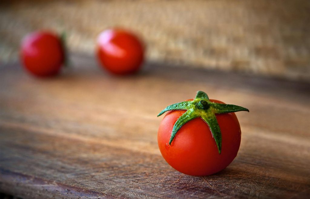 Vibrant cherry tomatoes resting on a rustic wooden surface, showcasing freshness and organic appeal.