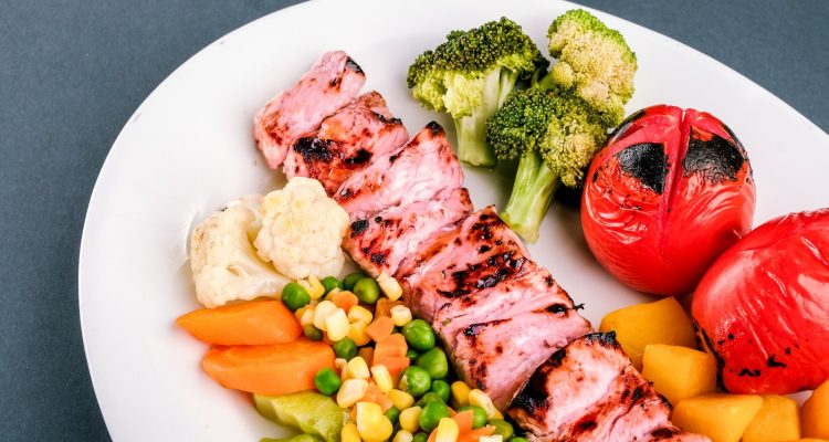 grilled meat with green vegetable and red chili on white ceramic plate